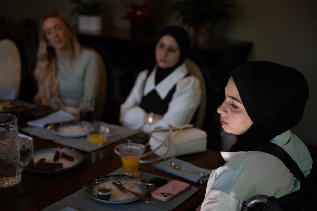 Ahed Bseiso, 18, right, recounts being in a building that was hit by an Israeli shell and subsequently having her leg amputated on her kitchen table last Dec. in Gaza while Dr. Reema Wahdan, not pictured, translates during breakfast at Dr. Omar Mubarak's home before an appointment to have a prosthetic leg fit at Hanger Clinic on Saturday, May 18, 2024, in Denver. Seated to the left of Bseiso is her sister Mona. (Photo by Timothy Hurst/The Denver Post)