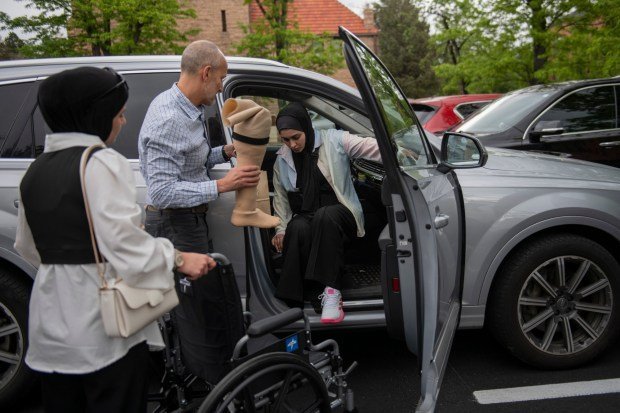Dr. Omar Mubarak, left, Vascular surgeon at the Vascular Institute of the Rockies, assists Ahed Bseiso, 18, with her prosthetic while loading into a car Saturday, May 18, 2024, in Boulder. Bseiso lost leg after the building she was in was hit by a shell in Gaza. Her leg was amputated on her kitchen table by her uncle who is an orthopedic surgeon. (Photo by Daniel Brenner/Special to The Denver Post)