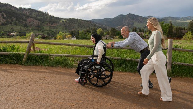 Dr. Omar Mubarak, Vascular surgeon at the Vascular Institute of the Rockies, pushes Ahed Bseiso, 18, in her wheelchair Saturday, May 18, 2024 at Chautauqua Park in Boulder Colorado. Bseiso lost leg after the building she was in was hit by a shell. Her leg was amputated on her kitchen table by her uncle who is an orthopedic surgeon. (Photo by Daniel Brenner/Special to The Denver Post)