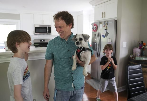 Joel Gratcyk holds their new dog Falkor as he hangs out with his sons Wesley, 11, left, and Theodore, 7, in their home in Arlington Heights on June 12, 2024. (Eileen T. Meslar/Chicago Tribune)