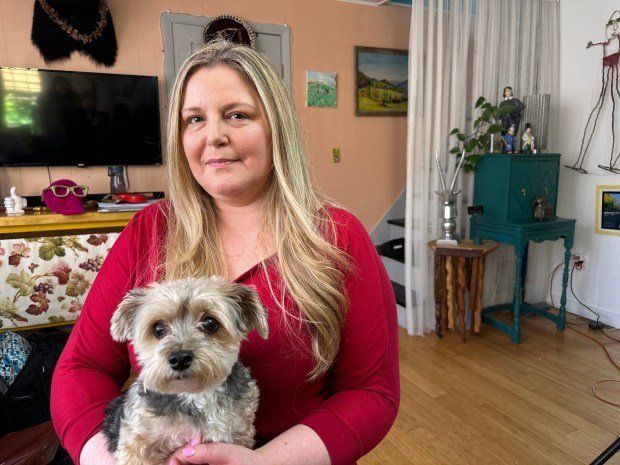 A woman in a red shirt holds her dog