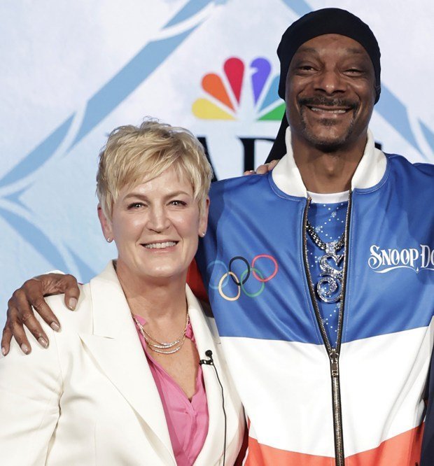 Rapper Snoop Dogg stands and smiles with a hand on the shoulder of NBC executive Molly Solomon